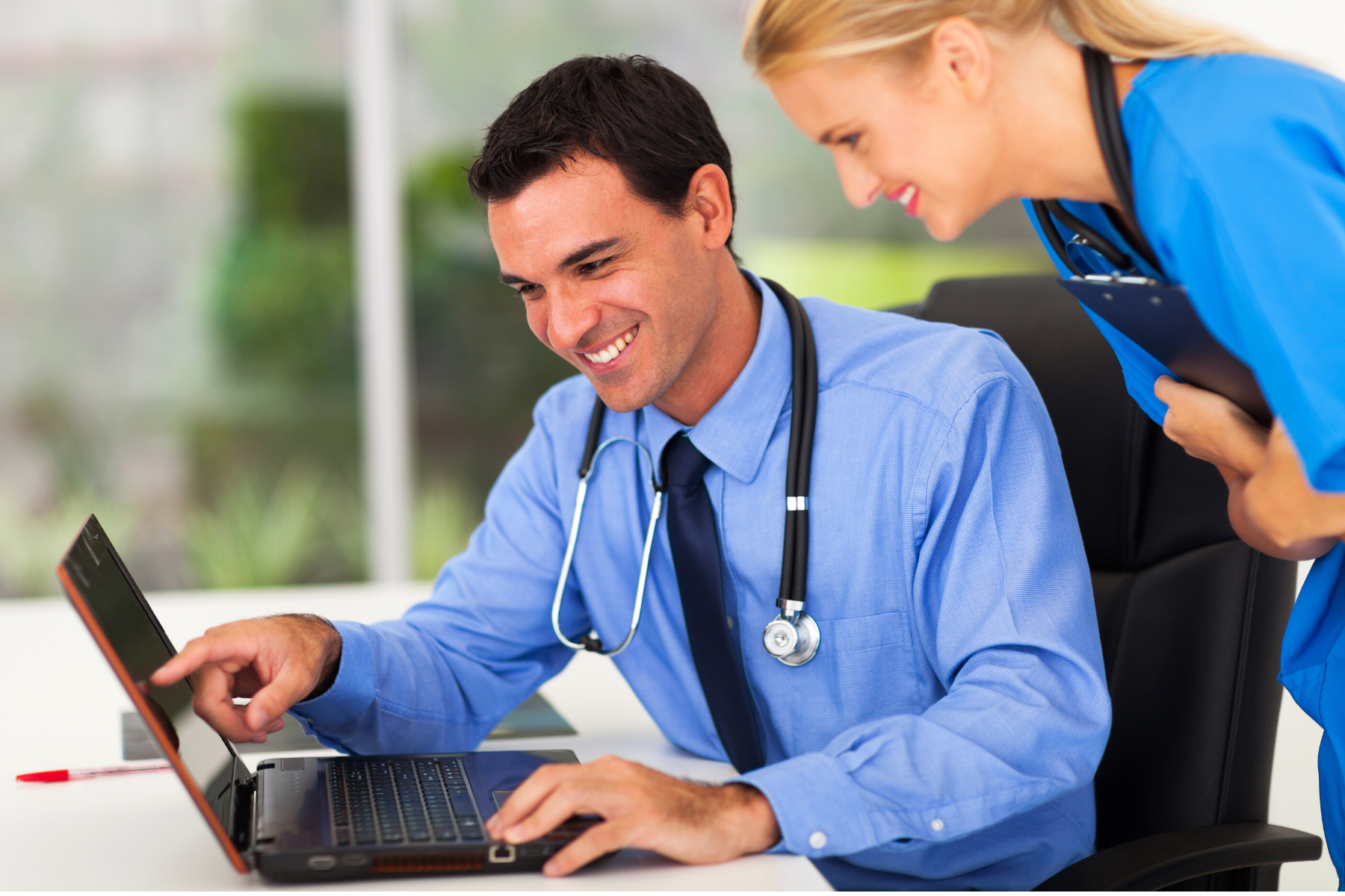 Doctor and nurse using hospital management software in UAE on a laptop with patient reports and dashboard